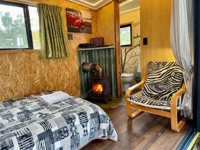 a bedroom with a bed and a chair and a wood stove at UnderHill Farm in Klipkraal