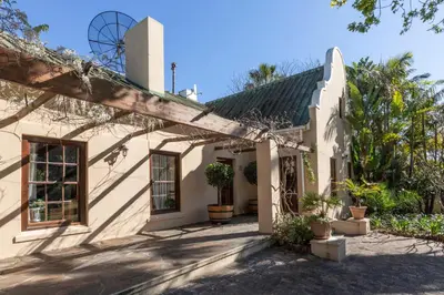an exterior view of a white house with plants at The Country Guesthouse in Stellenbosch