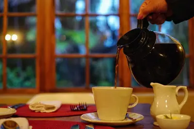 a person pouring coffee into a cup on a table at The Country Guesthouse in Stellenbosch