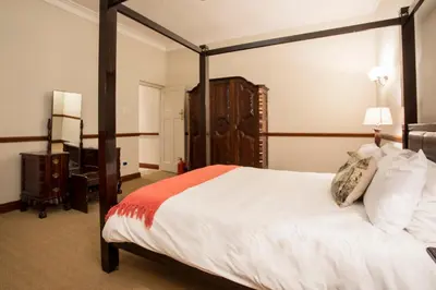 a bedroom with a canopy bed and a desk at The Country Guesthouse in Stellenbosch