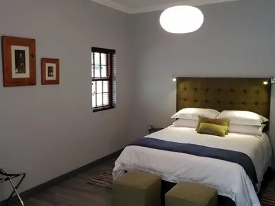 a bedroom with a large bed in a white room at Port Del Mar Guesthouse in Hermanus