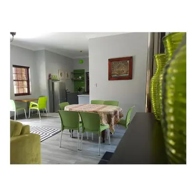 a dining room with a table and green chairs at Port Del Mar Guesthouse in Hermanus