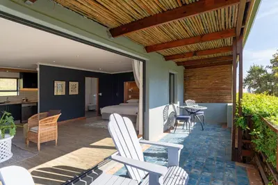 a patio with white chairs and a bedroom at Mont Angelis in Stellenbosch