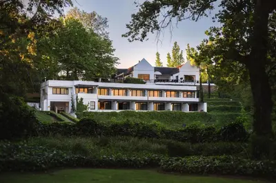 a large white house on a hill with trees at MolenVliet Estate - Boutique Bed & Breakfast in Stellenbosch