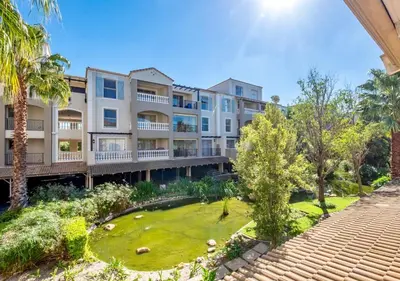 an apartment building with a lawn and palm trees at Bougain Villas in Cape Town