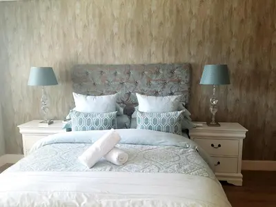 a bedroom with a large bed with two night stands at WATERS EDGE 103 in Cape Town