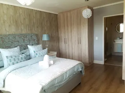 a bedroom with a large white bed with blue pillows at WATERS EDGE 103 in Cape Town