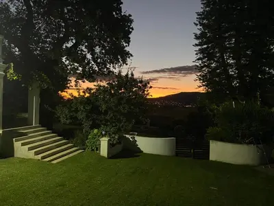 a garden with stairs and a sunset in the background at Hartebeeskraal House in Paarl