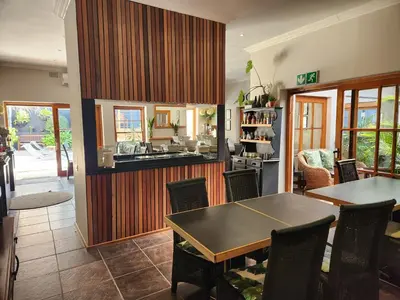 a dining room with a table and a kitchen at Little Scotia in Cape Town