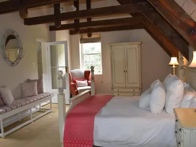 a bedroom with a large bed and a chair at Franschhoek Rose Cottages in Franschhoek