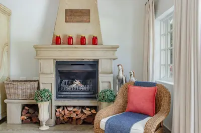 a living room with a fireplace and a chair at Franschhoek Rose Cottages in Franschhoek