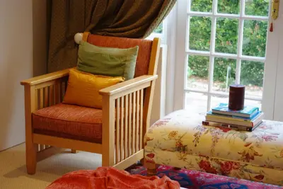 a room with a chair and a window with books at Lyngrove Wines & Guesthouse in Stellenbosch