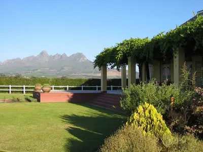 a house with a garden with mountains in the background at Lyngrove Wines & Guesthouse in Stellenbosch