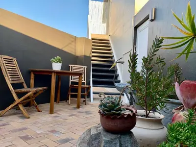 a patio with a table and chairs and potted plants at Anchor's Rest in Hermanus