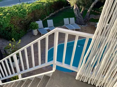 a swimming pool with chairs and a white railing at Anchor's Rest in Hermanus