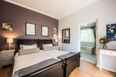 a bedroom with a large bed and a bathroom at Greenlawns B&B in Cape Town