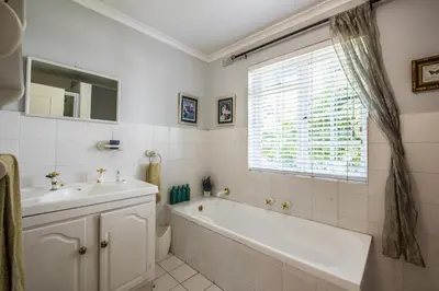 a bathroom with a tub and a sink and a window at Greenlawns B&B in Cape Town