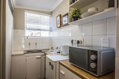 a small kitchen with a microwave and a sink at Greenlawns B&B in Cape Town