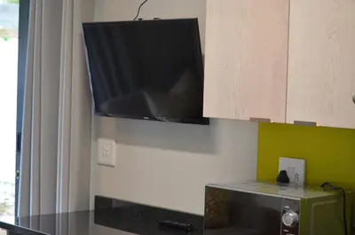 a television hanging on a wall in a kitchen at Columbine Place in Durbanville