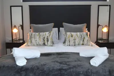 a large bed with white sheets and pillows at Columbine Place in Durbanville