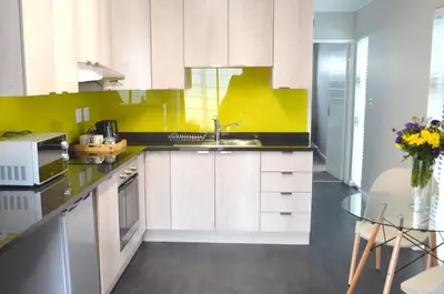 a kitchen with white cabinets and a yellow wall at Columbine Place in Durbanville