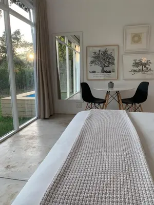 a white bedroom with a bed and a large window at Gite in Franschhoek