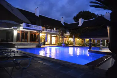 a large swimming pool in front of a house at night at Ridgemor Villa in Somerset West