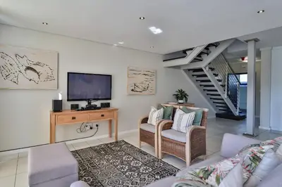 a living room with two chairs and a tv at Whale Coast All-Suite-Hotel - DCC Hotel Group in Hermanus