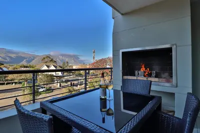 a balcony with a fireplace and a table and chairs at Whale Coast All-Suite-Hotel - DCC Hotel Group in Hermanus