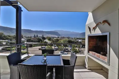 a balcony with a table and chairs and a fireplace at Whale Coast All-Suite-Hotel - DCC Hotel Group in Hermanus