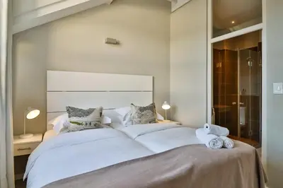a bedroom with a large white bed with a teddy bear at Whale Coast All-Suite-Hotel - DCC Hotel Group in Hermanus