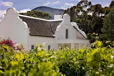 a white church with a mountain in the background at Holden Manz Country House in Franschhoek