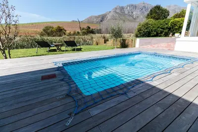 a swimming pool on a deck with a table and chairs at Charming Villa in Stellenbosch