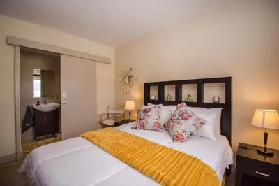a bedroom with a large white bed with pillows and a sink at Ocean View Luxury Self-Catering in Strand