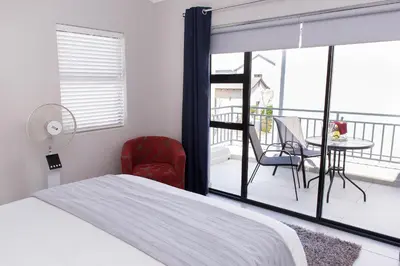 a bedroom with a bed and a balcony with a table and chairs at MLMK Property 30 in Richwood
