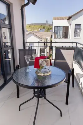 a table on a balcony with a glass at MLMK Property 30 in Richwood