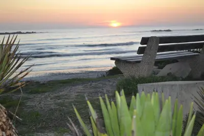 a bench sitting on the beach at sunset at Zeezicht 303 in Bloubergstrand
