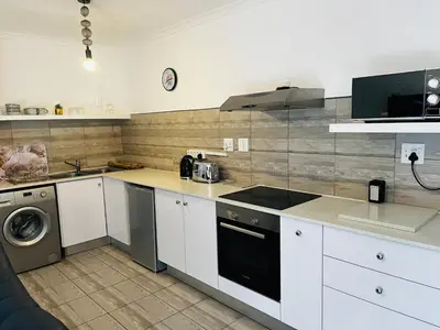 a kitchen with white cabinets and a washer and dryer at Modern secure apartment in Strand - Little Greece in Strand