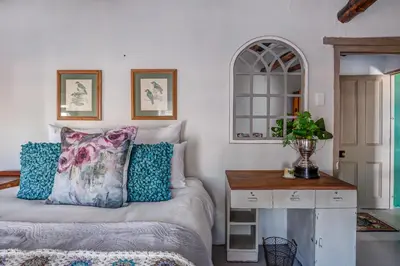 a bedroom with a bed with pillows and a table at De Kale Kat in Greyton