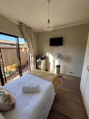 a bedroom with a large white bed with a large window at Amru Guesthouse B&B in Brackenfell