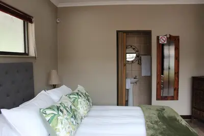 a bedroom with a white bed and a shower at Amru Guesthouse B&B in Brackenfell