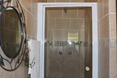 a bathroom with a shower with a mirror at Amru Guesthouse B&B in Brackenfell