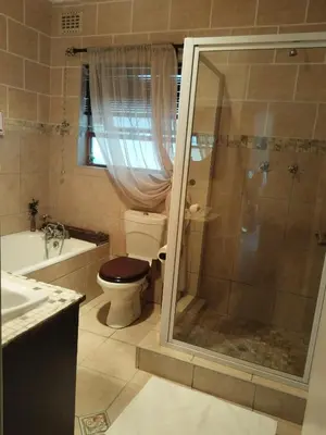 a bathroom with a shower and a toilet and a sink at Amru Guesthouse B&B in Brackenfell