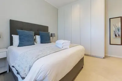a bedroom with a large bed with blue pillows at Axis Luxury Apartments by Century City Hotels in Cape Town