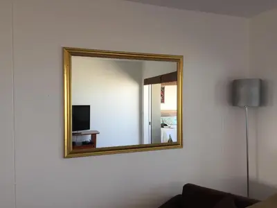 a mirror on a wall with a couch and a television at Ocean View B1001, Blouberg in Bloubergstrand