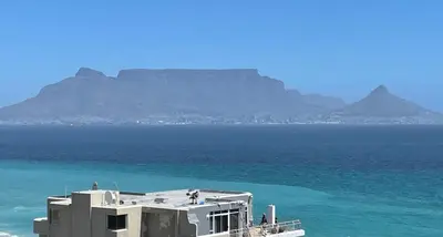 a building in the ocean with a mountain in the background at Ocean View B1001, Blouberg in Bloubergstrand