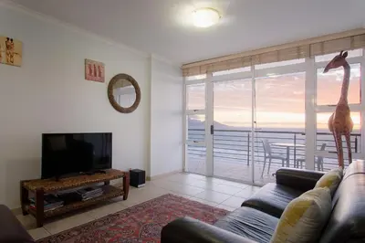 a living room with a couch and a television at The Waves Blouberg Beach Apartments in Bloubergstrand
