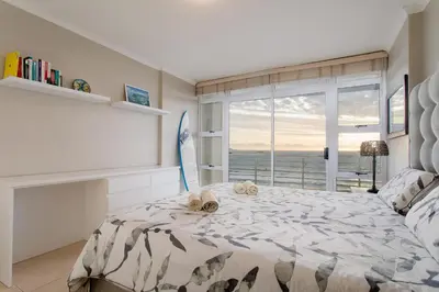 a bedroom with a bed with a view of the ocean at The Waves Blouberg Beach Apartments in Bloubergstrand
