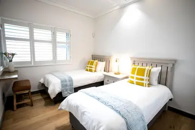 a bedroom with two beds with yellow and blue pillows at Bayview 303 in Hermanus