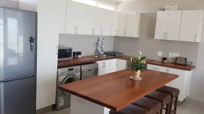 a kitchen with a wooden table and a refrigerator at 604 St Tropez in Strand